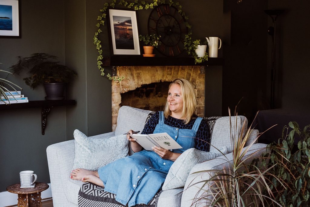 julia is wearing a denim pinafore and is cosy in her fave chair